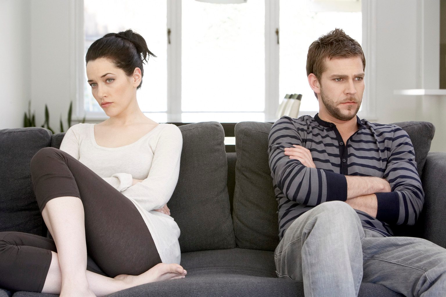 Couple sitting on sofa with anger on each other