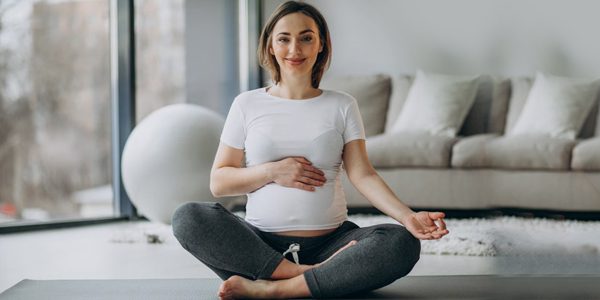 pregnant woman practicing yoga at home