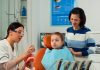 dentist-telling-kid-procedure-holding-sample-human-jaw