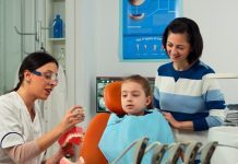 dentist-telling-kid-procedure-holding-sample-human-jaw