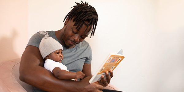 A Man Reading a Book to his Baby