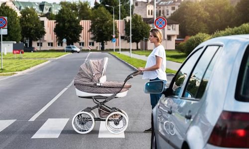 Young woman crossing the road with a stroller